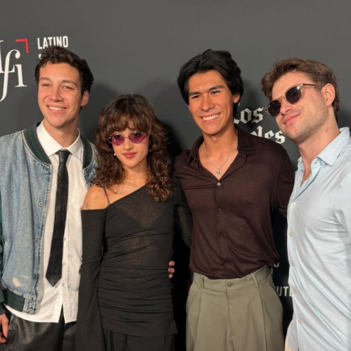 Fotografía de un grupo de actores posando en un evento cinematográfico con fondo institucional.
