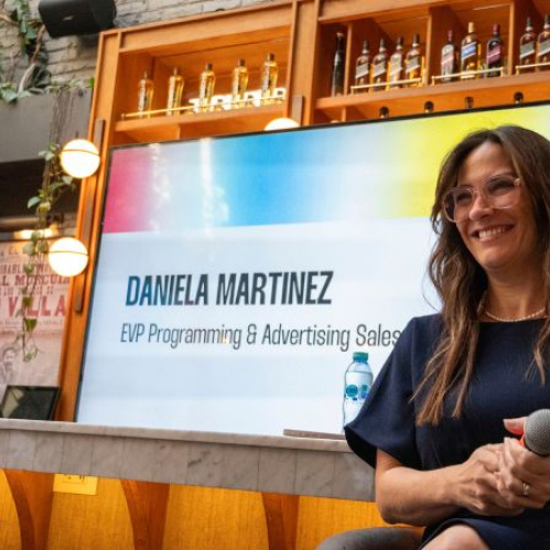 Fotografía de una presentación corporativa con una ejecutiva frente a una pantalla que muestra información institucional.