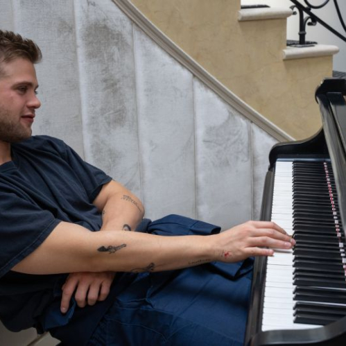 Personaje tocando un piano, acompañado de elementos visuales relacionados con el sonido.