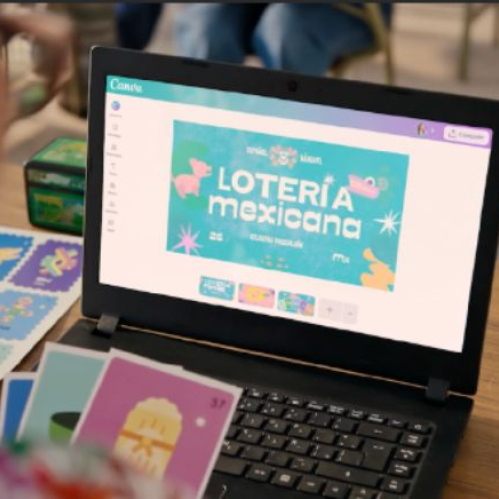 Una docente trabajando frente a una laptop negra abierta donde se observa en pantalla el diseño de la Lotería Mexicana en Canva, rodeada de tarjetas impresas sobre una mesa de madera.