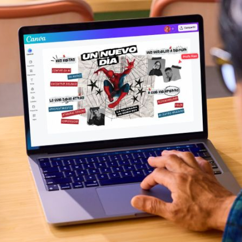 Persona trabajando en una computadora portátil sobre un escritorio de madera. En la pantalla de la laptop se muestra la interfaz de Canva con una plantilla de la colección oficial de Spider-Man: Un Nuevo Día, destacando una ilustración al centro del héroe en un mapa conceptual interactivo con textos personalizables. En la esquina superior derecha se aprecia la marca de derechos de autor © 2026 MARVEL.
