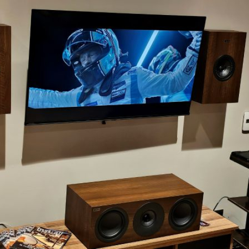 Sistema de entretenimiento en casa con pantalla, bocinas y equipo de audio en un entorno doméstico.