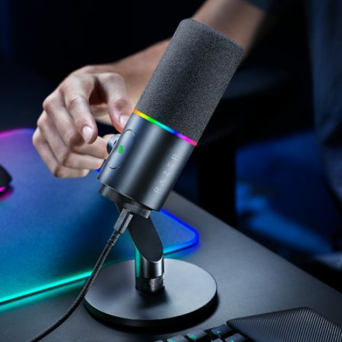 Primer plano de un micrófono con iluminación RGB en un entorno de escritorio para gaming o streaming.