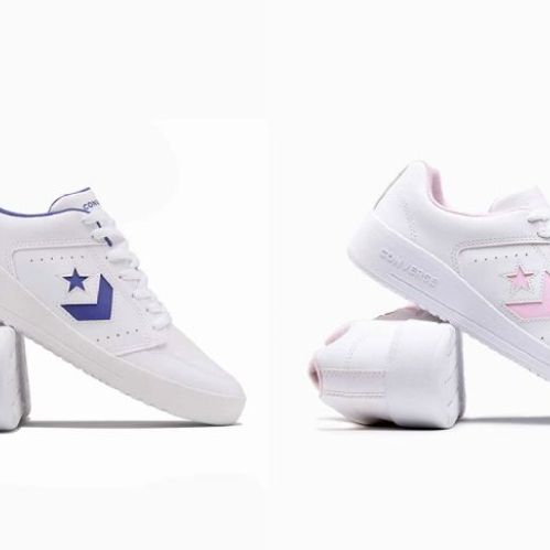 Fotografía de producto con fondo blanco que muestra dos pares de tenis deportivos de corte bajo en color blanco; el par izquierdo presenta el logotipo en forma de estrella y chevrón junto con el forro interno en color morado, mientras que el par derecho lleva los mismos detalles en tono rosa pastel.