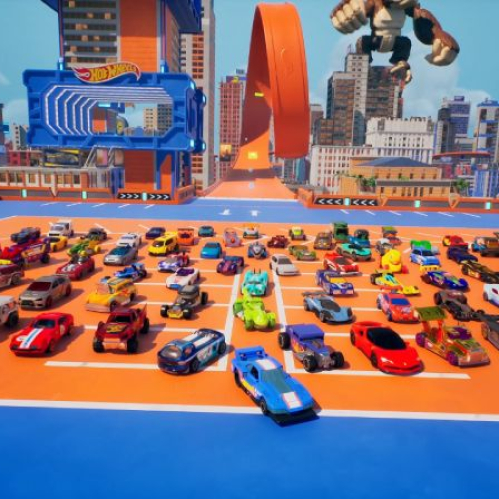 Decenas de carritos de juguete Hot Wheels de diversos colores y estilos alineados en una plataforma azul y naranja, con rascacielos y una pista naranja gigante de fondo bajo un cielo azul.