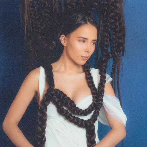 Retrato artístico de una mujer con un vestido blanco y una elaborada estructura de trenzas que rodean su cuerpo, sobre un fondo azul.