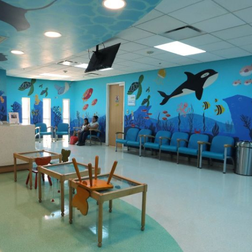 Sala de espera infantil decorada con temática marina y mobiliario adaptado para niñas y niños.