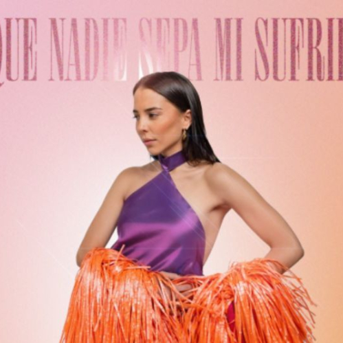 Majo Aguilar posa de perfil con la cabeza ligeramente inclinada luciendo un vestido morado de cuello halter y una capa naranja de tiras o flecos sobre un fondo con degradado rosa y naranja, con el titulo Que Nadie Sepa Mi Sufrir en la parte superior y su nombre en la parte inferior.