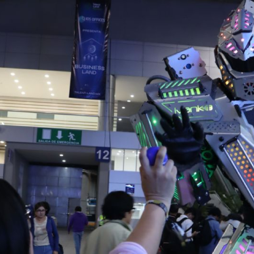 Persona interactuando con un robot humanoide iluminado con luces de colores en un evento tecnológico.