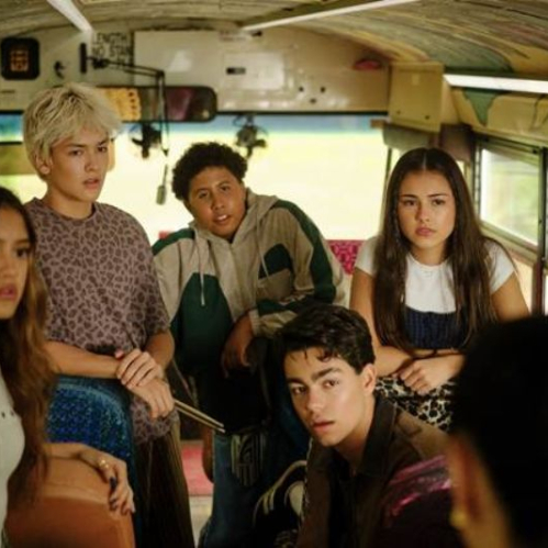 Grupo de jóvenes actores del elenco de Camp Rock 3 sentados en el interior de un autobús escolar decorado con grafitis en el techo. En primer plano a la izquierda destaca una joven con cabello castaño largo y blusa blanca con detalles metálicos; detrás de ella, un joven de cabello rubio platinado y camisa de estampado de leopardo; al fondo, un joven con sudadera verde y gris; a la derecha, una joven de cabello castaño mirando fijamente hacia el frente.