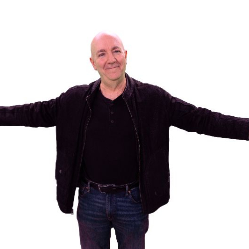 Retrato de cuerpo entero del locutor y conductor Iñaki Manero sobre un fondo negro plano. Viste una chamarra de piel negra, playera oscura con botones al frente y jeans azules. Aparece con los brazos abiertos extendidos hacia los lados y una sonrisa ligera.