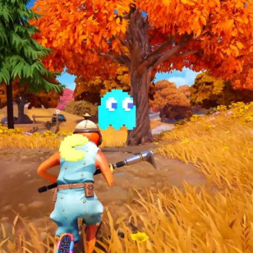 Captura de pantalla de jugabilidad de Fortnite en un entorno de bosque de otoño con árboles de hojas anaranjadas. En el centro aparece un personaje equipado con un disfraz naranja y la mochila de PAC-MAN, mientras que en el aire flota un fantasma pixelado de color azul claro inspirado en el juego clásico de PAC-MAN.
