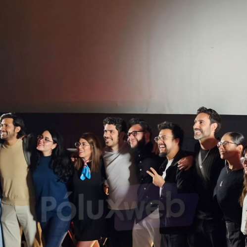 El elenco completo de voces y equipo de producción del doblaje latino de Black Torch posando juntos y sonrientes frente a la pantalla en una sala de proyección.