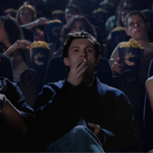Fotografía fija del spot de Cinépolis "Hechos de Cine". En una sala de cine oscura y con la iluminación ambiental de la pantalla, aparecen sentados de izquierda a derecha Jacob Batalon, Tom Holland y Zendaya disfrutando de una función. Jacob Batalon lleva lentes y sostiene un bote de palomitas con el logotipo de Cinépolis, al igual que Tom Holland, quien come palomitas con una mano, mientras que Zendaya observa hacia un costado con expresión seria y elegante vestimenta oscura. De fondo, otros espectadores disfrutan de la función.