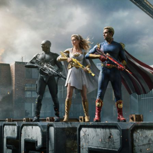 Tres personajes con trajes de estilo superhéroe posan en una estructura urbana mientras el entorno muestra humo, fuego y un helicóptero en el fondo.