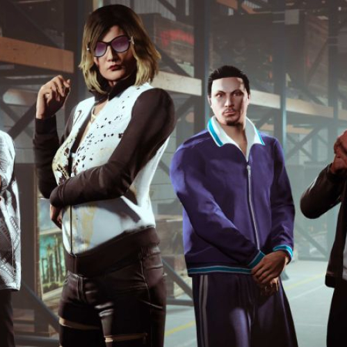 Captura de pantalla de GTA Online que muestra a cuatro personajes vestidos de forma distinta dentro de un almacén industrial con estanterías metálicas y palés de madera de fondo. En primer plano a la izquierda, un hombre con gafas de sol oscuras y camisa de manga corta estampada con patrones geométricos grises y blancos tiene los brazos cruzados. A su lado, una mujer con gafas de sol moradas, cabello rubio corto y una chaqueta de chándal blanca y negra estampada posa con una mano en la barbilla. A la derecha de ella, un hombre joven con el cabello corto peinado hacia atrás viste un chándal azul deportivo con detalles blancos en el cuello y puños. En el extremo derecho, un hombre con gafas de sol marrones y chaqueta de cuero marrón tiene las manos entrelazadas sobre el pecho. En la esquina inferior izquierda se aprecian cuadros y marcos de arte antiguos.