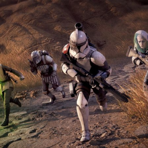 Captura de pantalla de gameplay de Star Wars Zero Company que muestra a un escuadrón de cuatro operadores avanzando en fila por un camino de piedra en un entorno árido con hierba seca. En primer plano, al centro, encabeza la Marcha un Clon Trooper con armadura blanca desgastada y marcas de batalla. A la izquierda, una joven Padawan alienígena vistiendo túnicas Jedi sostiene un sable de luz de hoja verde encendida. Detrás del Clon avanza un guerrero Mandalorian con armadura blanca y roja equipada con jetpack. A la derecha, un tirador de élite porta un casco protector de burbuja transparente y un rifle de precisión.