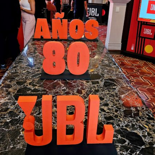 Instalación con letras volumétricas naranjas y elementos decorativos alusivos a un evento temático.