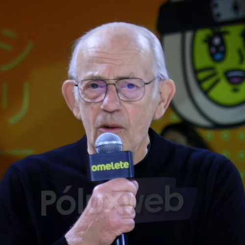 Persona mayor sosteniendo un micrófono en un escenario con fondo ilustrado y estética pop cultural.