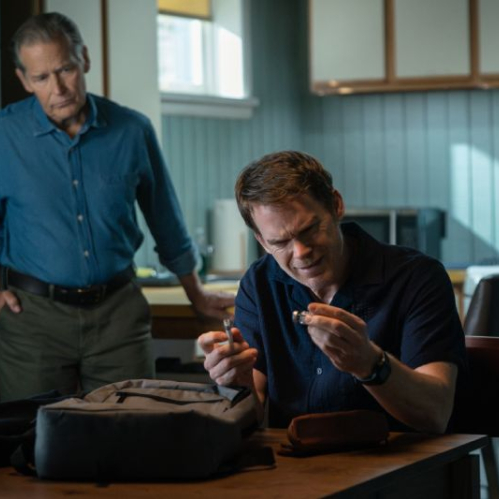 Fotografía promocional de la serie en plano medio dentro de una cocina. En primer plano a la derecha, Michael C. Hall como Dexter Morgan vistiendo una playera polo azul marino se encuentra sentado frente a una mesa de madera sosteniendo un pequeño frasco de vidrio en sus manos con expresión preocupada. En segundo plano a la izquierda, James Remar como Harry Morgan viste camisa de mezclilla azul y pantalón beige, parado con las manos en los bolsillos observando detenidamente a Dexter. De fondo se aprecia una estufa blanca y gabinetes de cocina.
