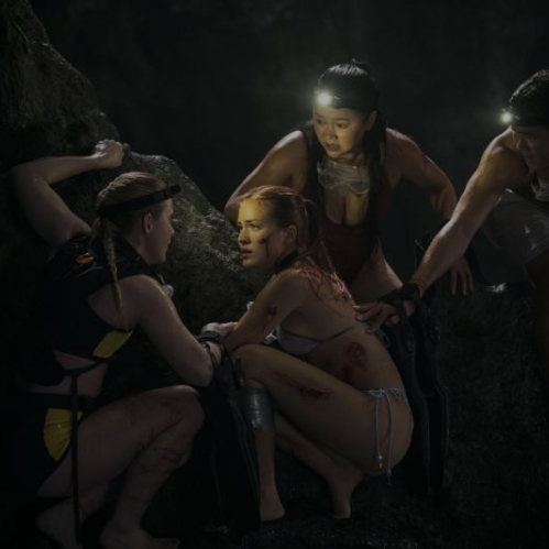 Grupo de jóvenes dentro de una cueva oscura, iluminados por lámparas frontales mientras auxilian a un integrante herido.