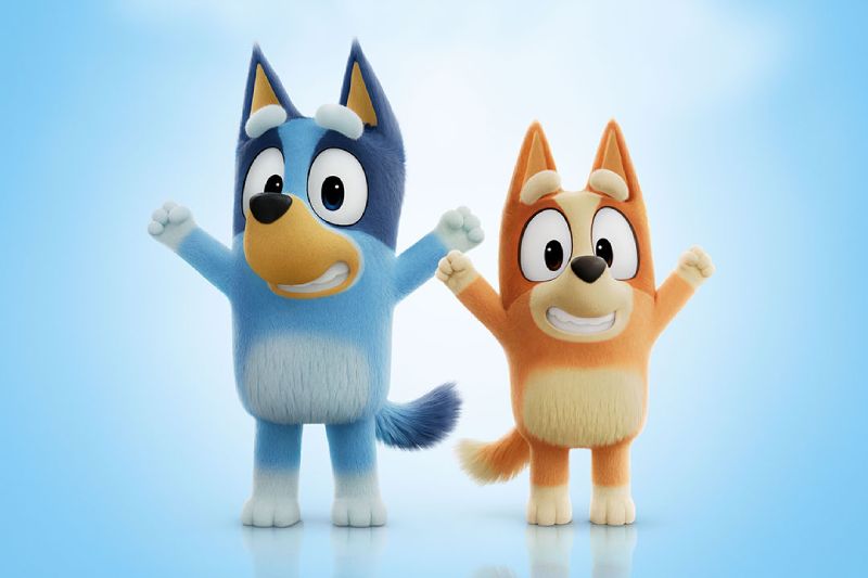 Ilustración en 3D/CGI de los personajes Bluey y Bingo celebrando con los brazos en alto sobre un fondo azul claro con nubes suaves.