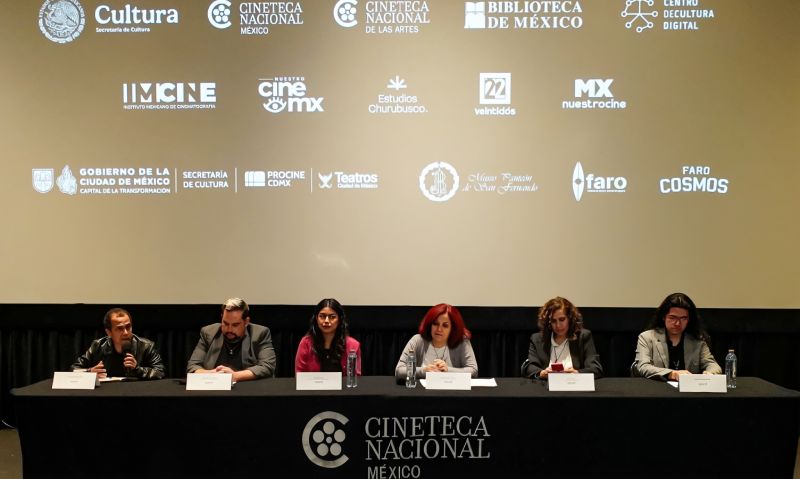 Presentación de la programación oficial de los XXV años de Macabro FICH en la Cineteca Nacional México. Fotografía de una conferencia de prensa en una sala de cine de la Cineteca Nacional México. Frente a una pantalla donde se proyectan los logotipos de la Secretaría de Cultura, Cineteca Nacional, IMCINE y Canal 22, seis ponentes se encuentran sentados detrás de una mesa de presídium cubierta con mantelería negra con el logotipo del recinto en blanco. Los ponentes cuentan con micrófonos y hojas sobre la mesa.