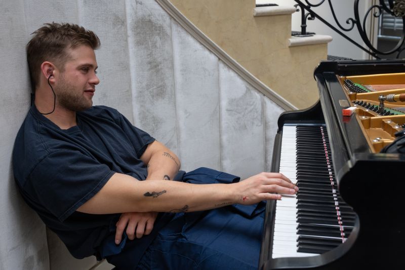El Afinador – Momento musical Personaje tocando un piano, acompañado de elementos visuales relacionados con el sonido.