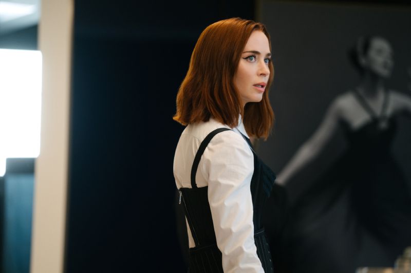 Emily en oficina – Moda 2 Persona con camisa blanca y prenda negra frente a una fotografía artística.
