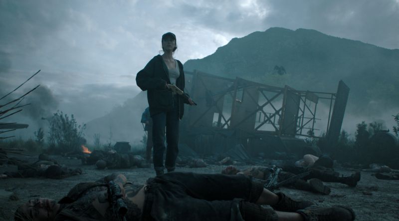 Margaret Qualley en un escenario devastado Margaret Qualley como Cima sosteniendo una escopeta de palanca en pie sobre un terreno devastado lleno de cuerpos tras un enfrentamiento.
