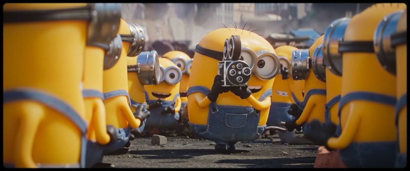 Minions & Monstruos — Rodaje improvisado Minion filmando con una cámara antigua mientras otros observan la escena.
