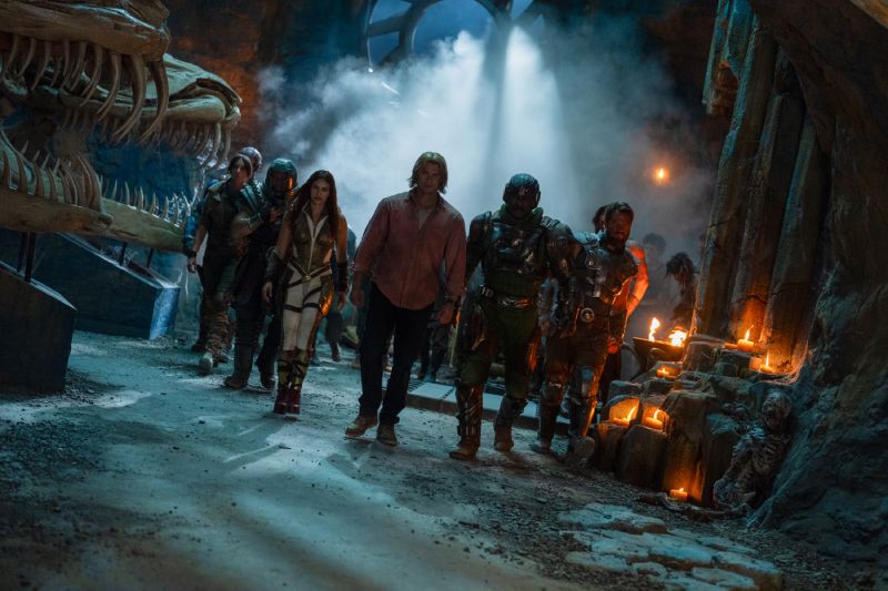 Grupo avanzando entre ruinas iluminadas por velas.