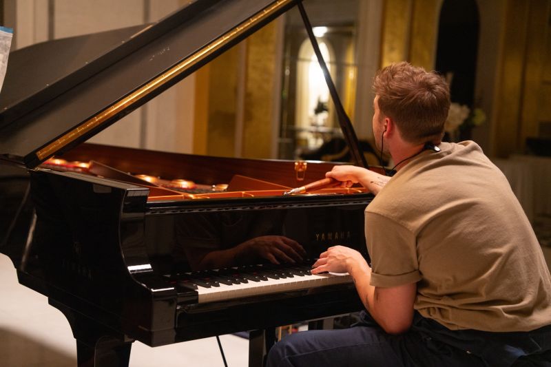 Persona afinando un piano de cola con herramientas profesionales.