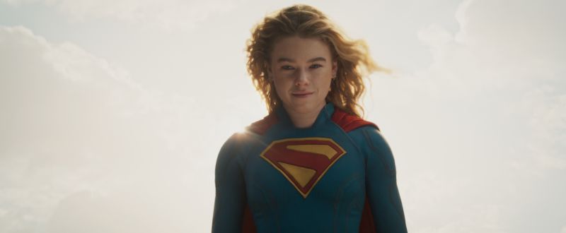 Supergirl — Iconografía clásica Figura de Supergirl iluminada por el sol mientras flota sobre un cielo despejado.