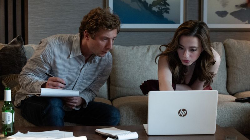 Investigación y Revelaciones Jeremy Allen White tomando notas mientras revisa documentos junto a Mikey Madison frente a una computadora portátil en una sala.