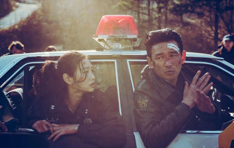 Hoyeon e Hwang Jung-min heridos y vendados asomados por las ventanas de la patrulla conversando con preocupación.
