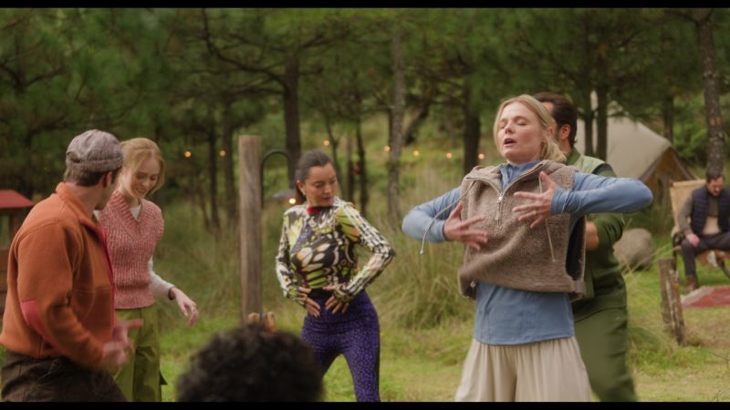 Grupo de personas realizando una dinámica de movimiento expresivo en círculo al aire libre rodeados de árboles.