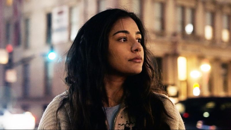 Reflexión sobre el perdón y la esperanza Retrato en primer plano de una joven mirando hacia el horizonte en un entorno urbano iluminado de noche.