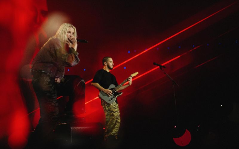 Emily Armstrong cantando en vivo en un escenario iluminado con luces rojas intensas durante una presentación de Linkin Park.
