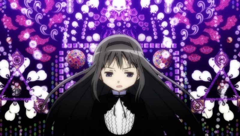 Homura Akemi en el universo abstracto de Rebellion Captura de pantalla de la película Puella Magi Madoka Magica: Rebellion centrada en Homura Akemi con expresión afligida sobre un fondo geométrico abstracto y recargado con patrones de púrpura, violeta y figuras góticas.