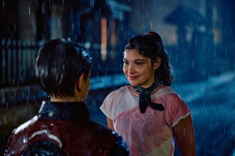 Vincent en un encuentro bajo la lluvia con su interés amoroso Una joven con pañoleta en el cuello sonríe bajo una lluvia nocturna mientras mira de frente a Vincent.