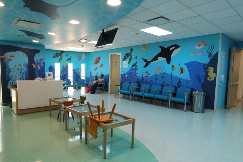 Shriners Children’s México – Área pediátrica Sala de espera infantil decorada con temática marina y mobiliario adaptado para niñas y niños.