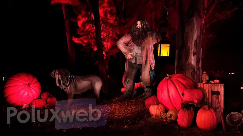 Figura animatrónica de Rubeus Hagrid sosteniendo una linterna junto a su perro Fang rodeados de calabazas gigantes bajo una luz roja escénica.
