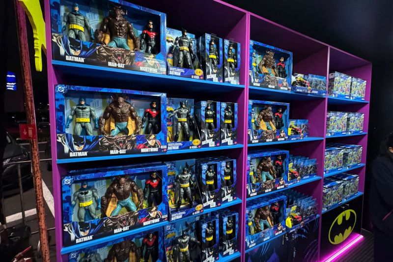 Estantes de exhibición de color morado cargados de figuras de acción y coleccionables de Batman, Man-Bat y Nightwing.