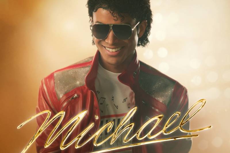 Retrato estilizado inspirado en Michael Jackson Persona con chaqueta roja y gafas oscuras posando frente a un fondo cálido iluminado, evocando una estética escénica asociada a la cultura pop.
