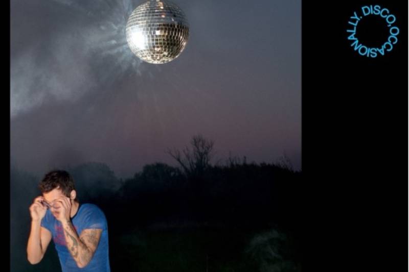 Figura en un entorno nocturno con una esfera disco suspendida sobre su cabeza, iluminando el paisaje con reflejos brillantes.