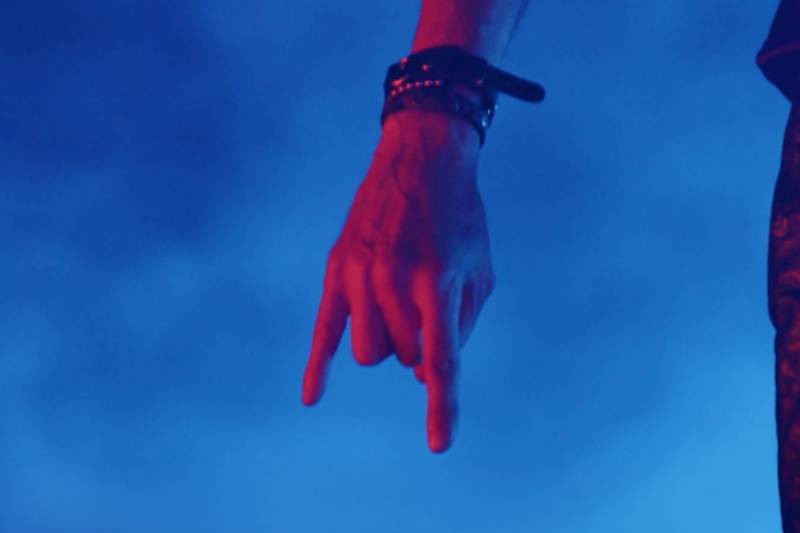 Primer plano de un brazo extendido hacia abajo sobre un fondo azul, acompañado del nombre de la banda y el título del lanzamiento.