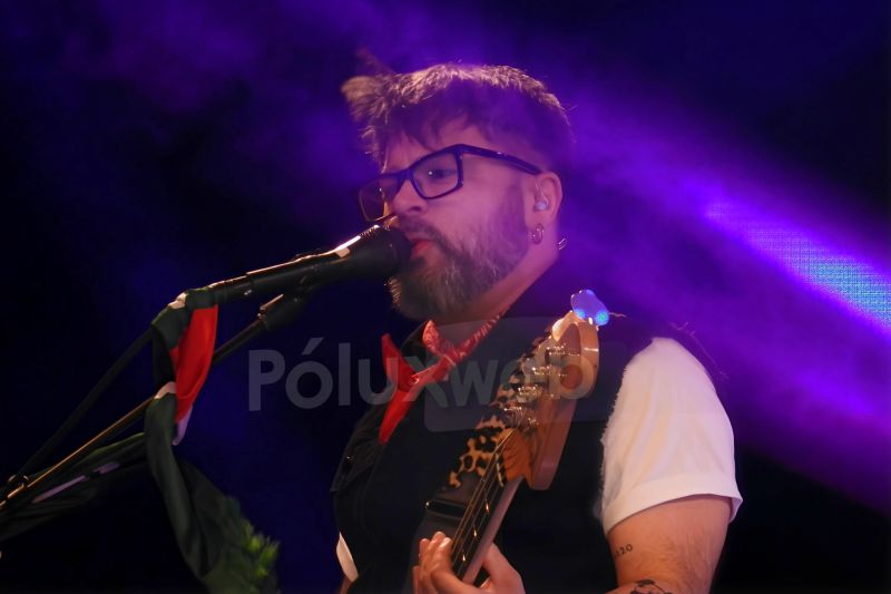 Bajista con bufanda roja tocando bajo luces púrpuras.