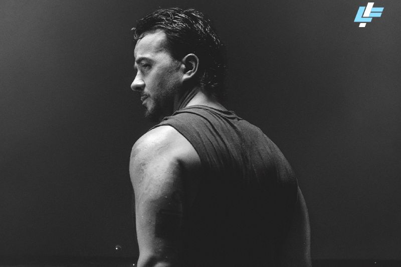 Luis Fonsi anuncia la gira Mar Infinito World Tour 2027 Fotografía en blanco y negro de Luis Fonsi de perfil sobre un fondo oscuro y sumergido parcialmente en agua, bajo el título de la gira en letras azules claras.