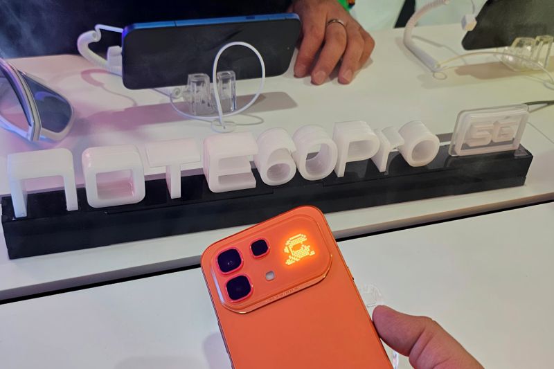 Smartphone en exhibición con iluminación distintiva junto a un letrero tridimensional del modelo NOTE 60 Pro 5G en un entorno de presentación tecnológica.